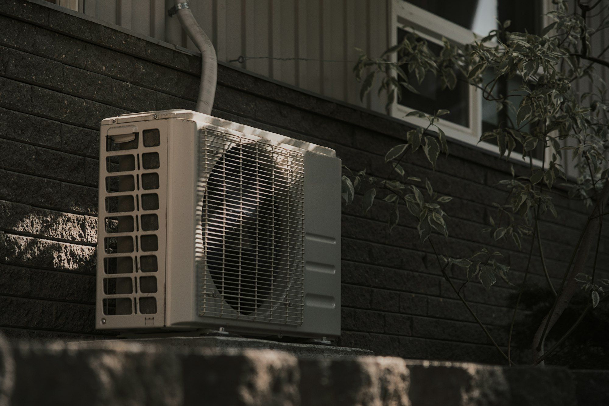 Outdoor AC condenser against a brick wall
