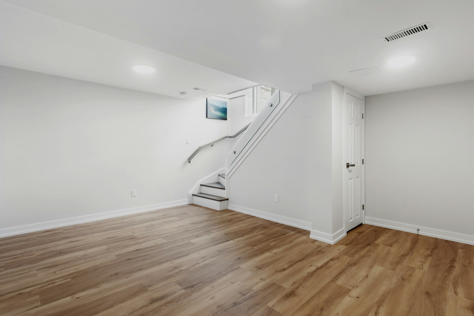 Finished basement room with new LVP flooring and white walls