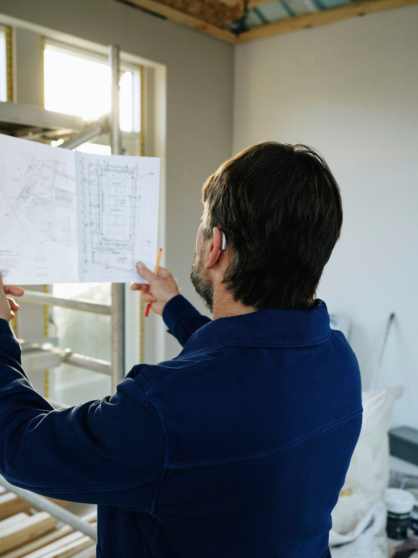 Mark checking a floor plan against an open wall on site