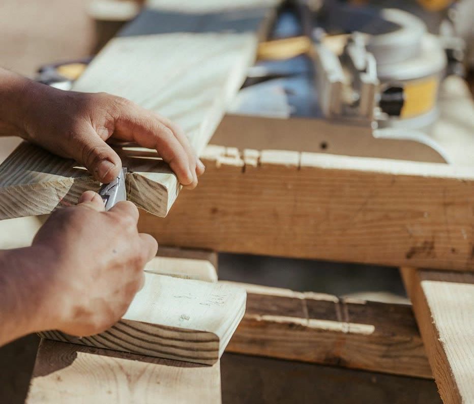 Carpenter's hands fitting a notched piece of wood beside a miter saw