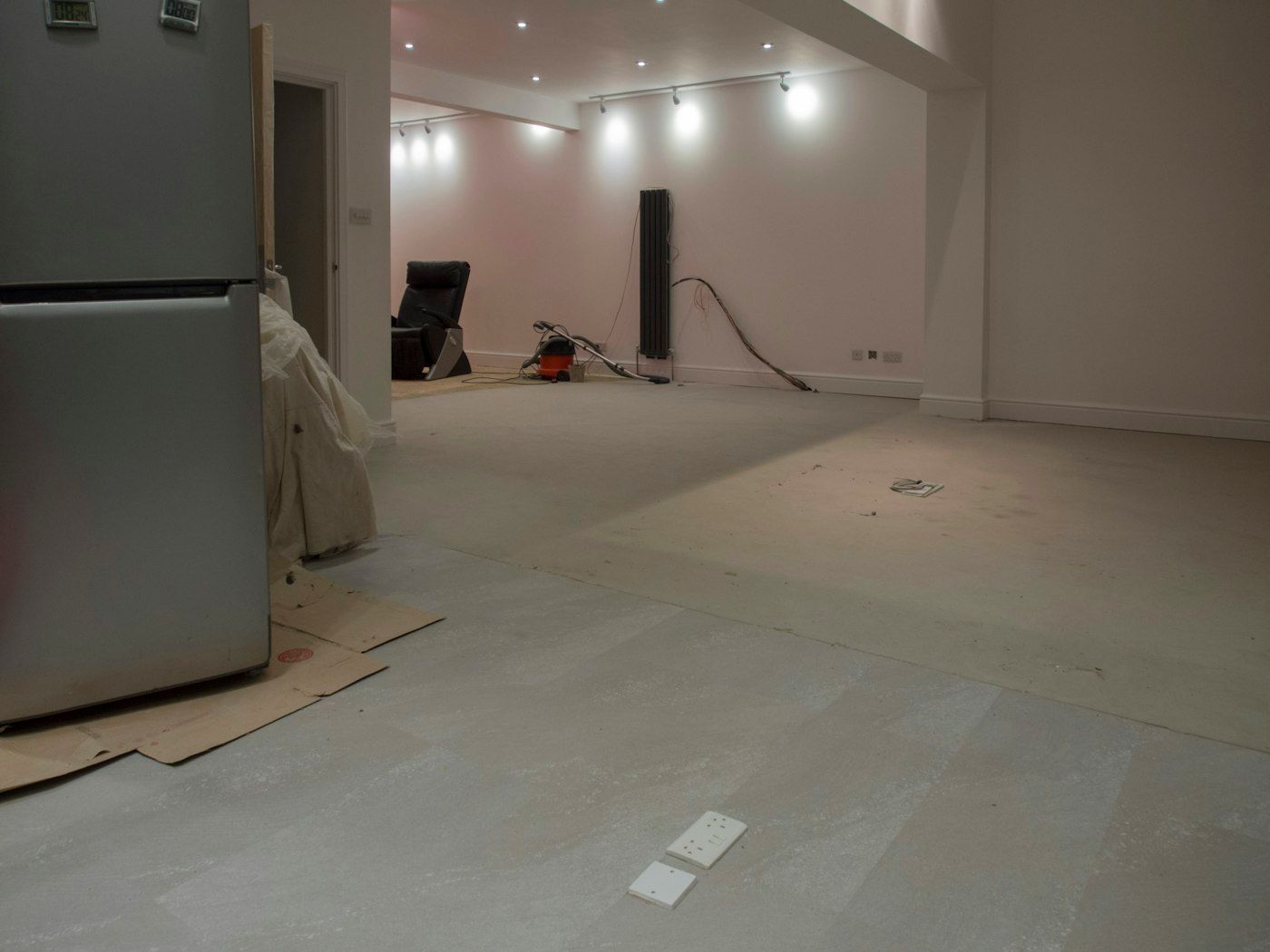 Cleared room with bare subfloor and protection paper at the edges