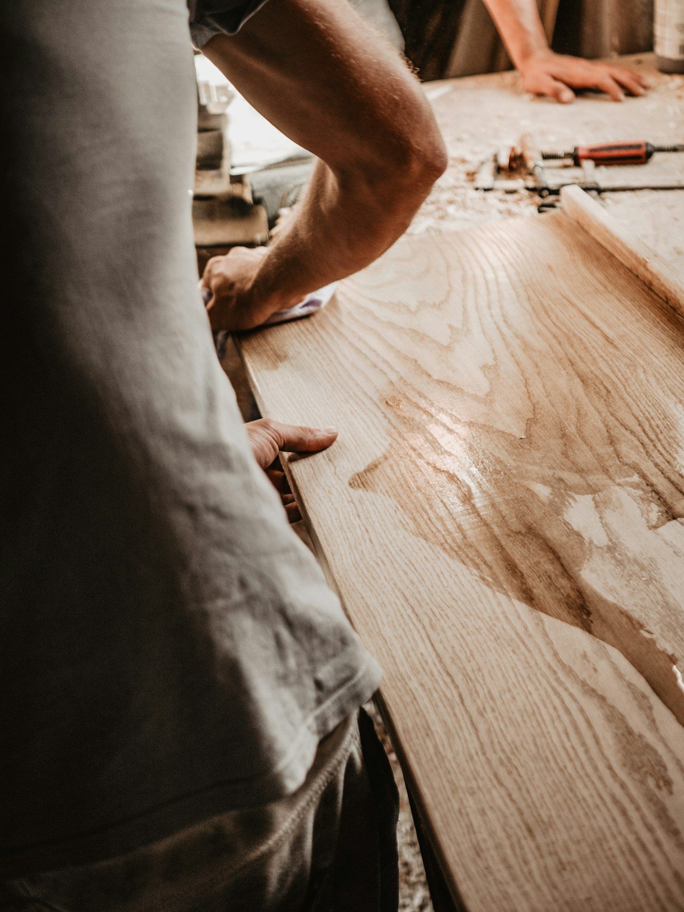 Carpenter's hands smoothing the edge of an oak board