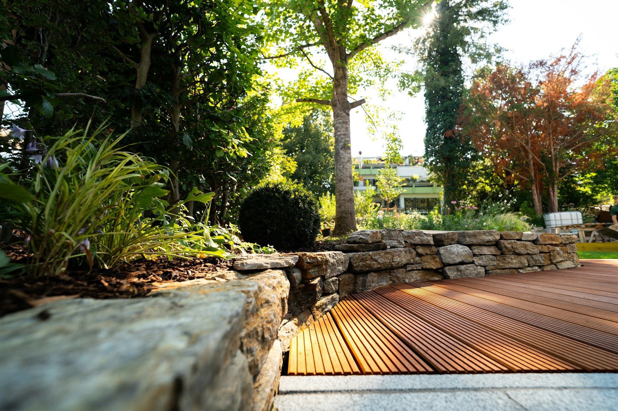 Hardwood deck meeting a dry-laid stone wall planted with grasses