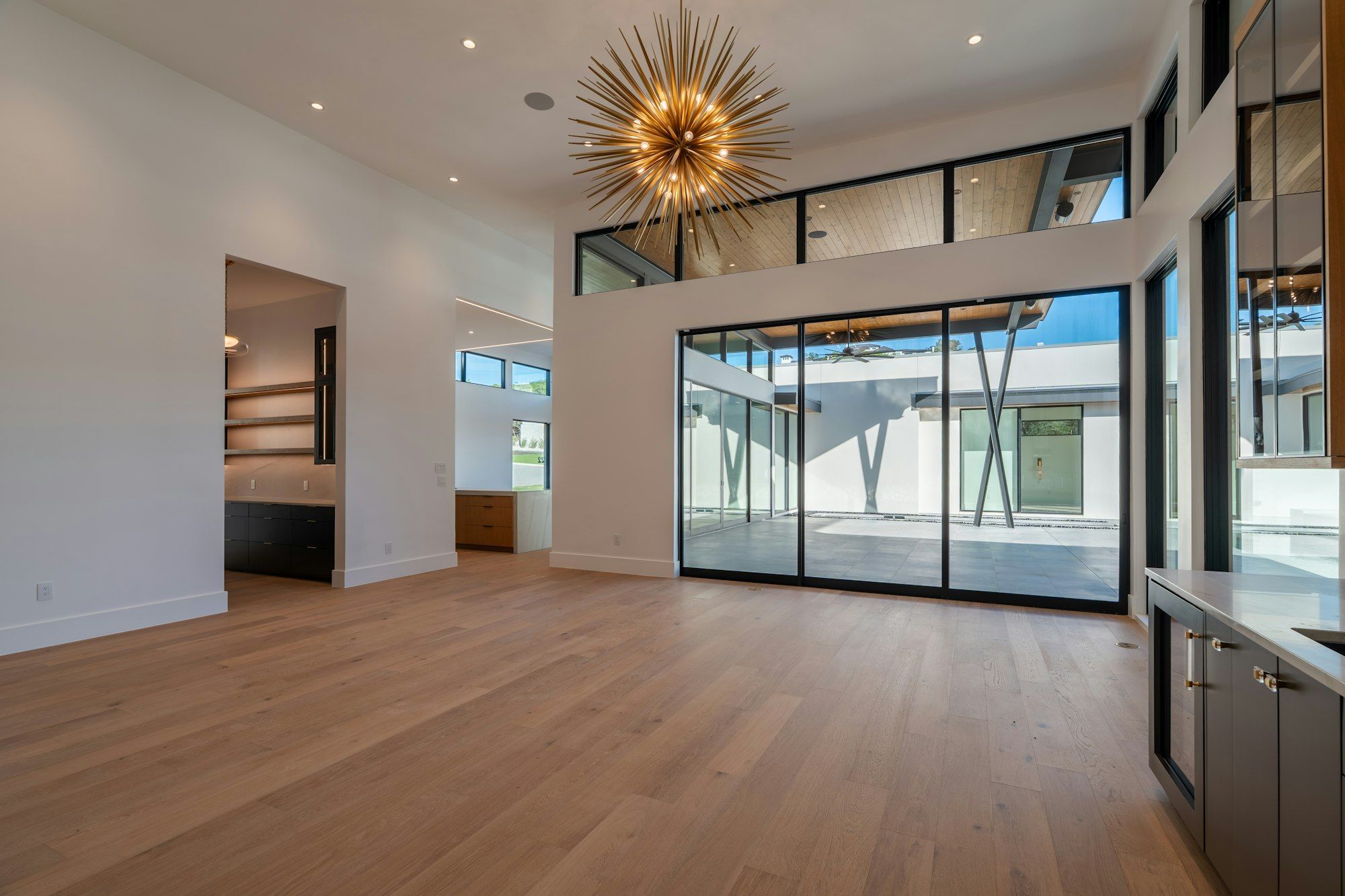 Large great room with wide plank oak floor and glass doors to a patio