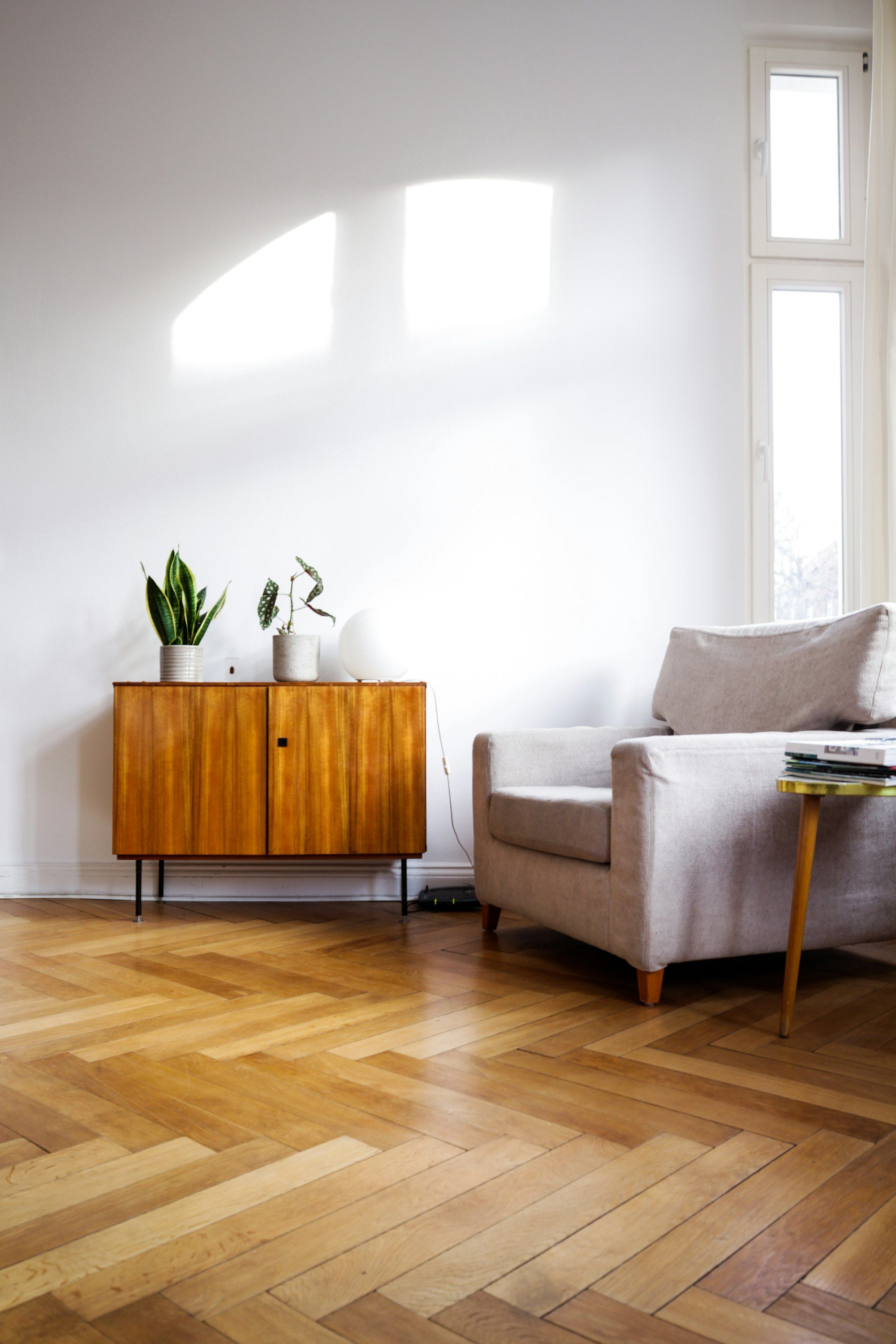 Sitting room with honey herringbone oak floor, armchair and walnut sideboard