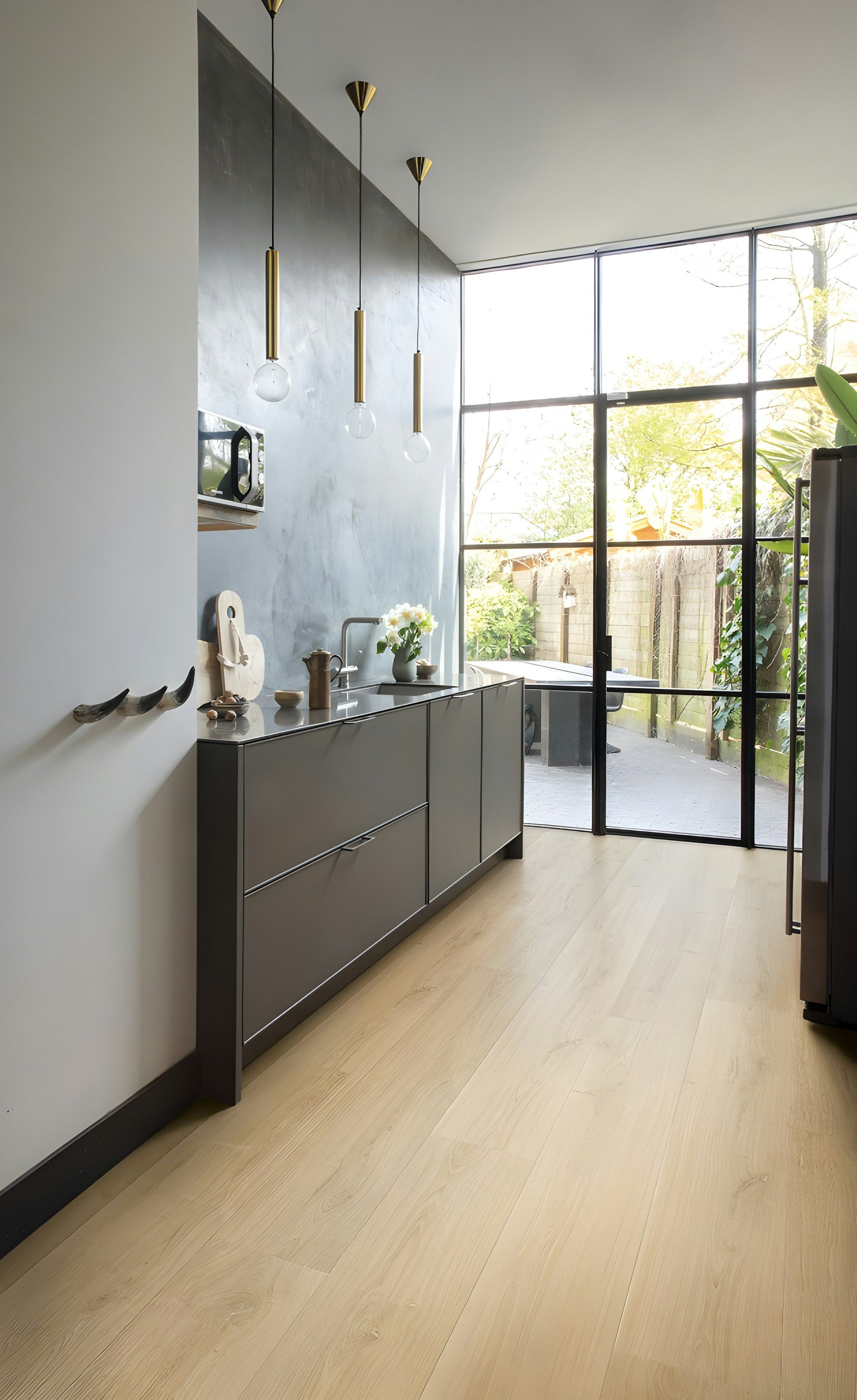 Narrow kitchen with dark cabinets and pale oak floor running to a glass door