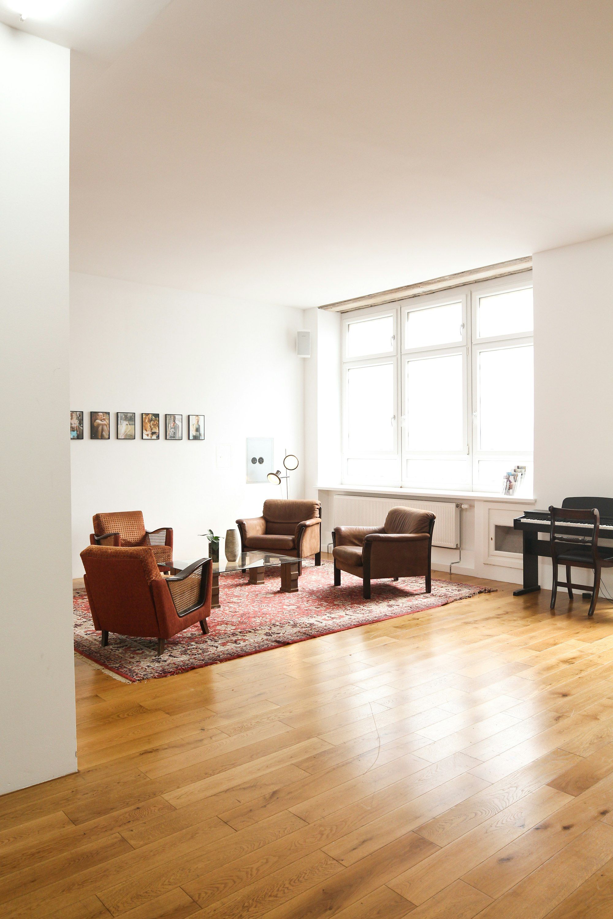 Bright loft living room with oiled oak planks, leather armchairs and a red rug