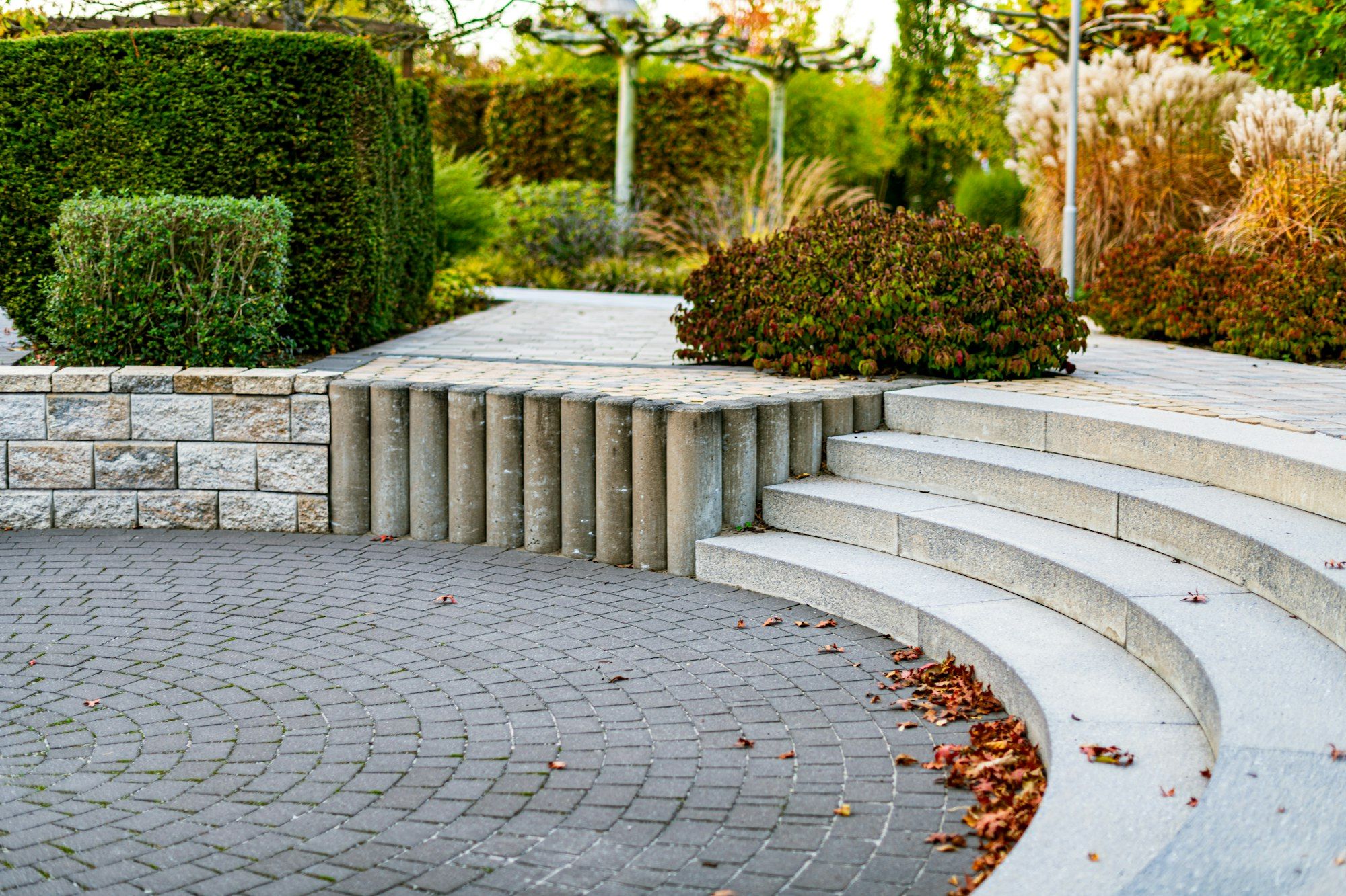 Curved granite steps leading down to a fan-pattern cobblestone patio
