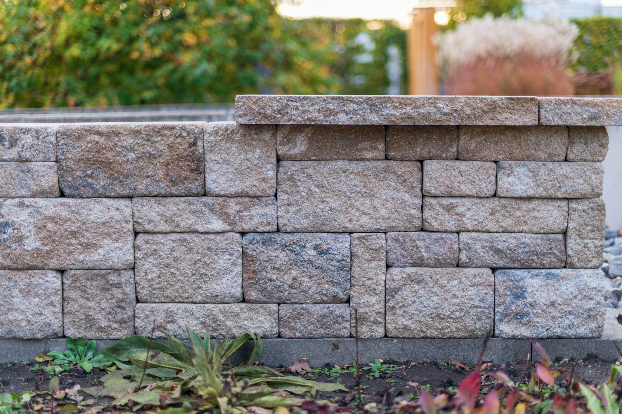 Tan split-face block garden wall with a capstone row
