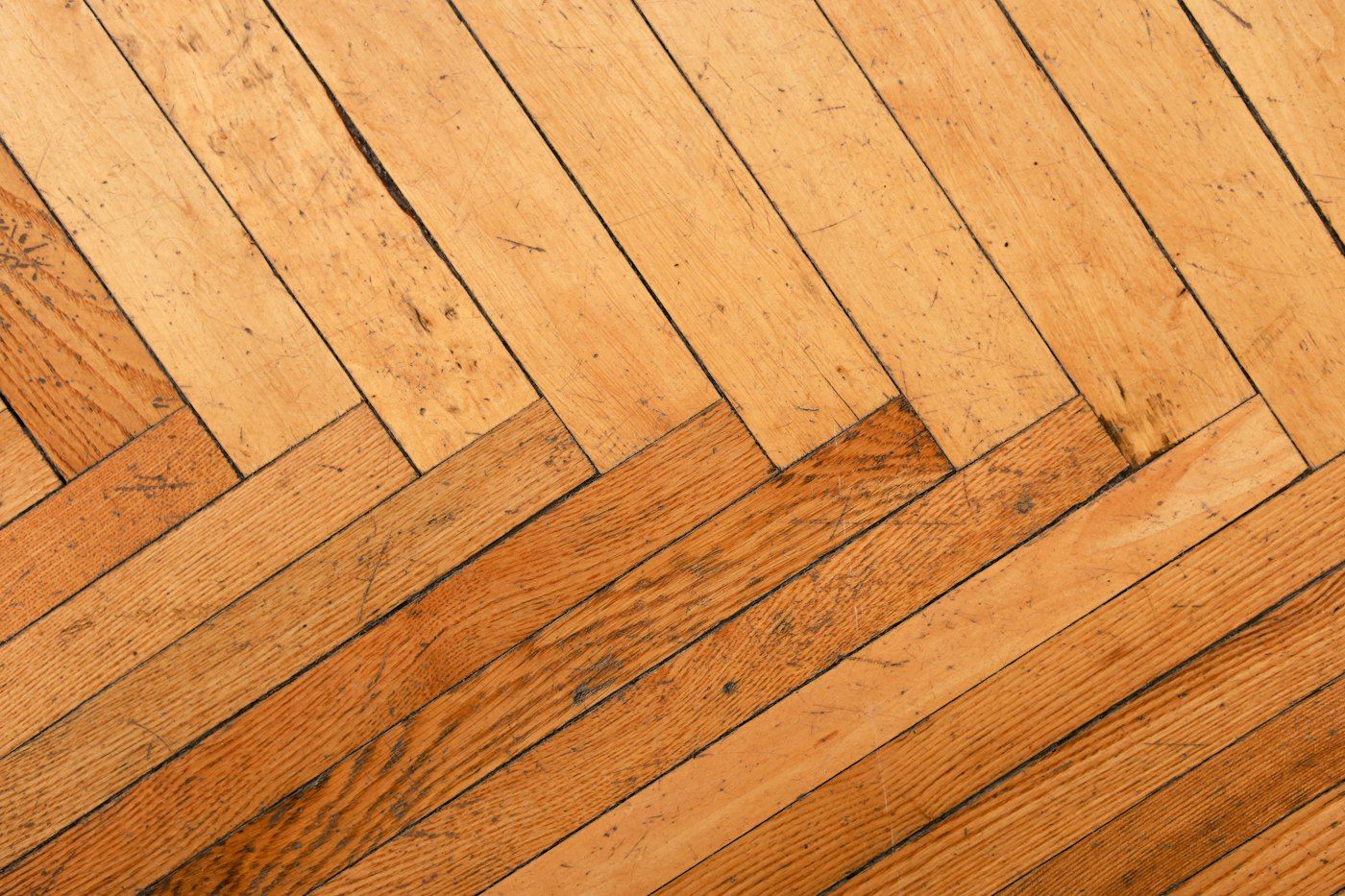 Close view of a worn herringbone oak floor with visible grain