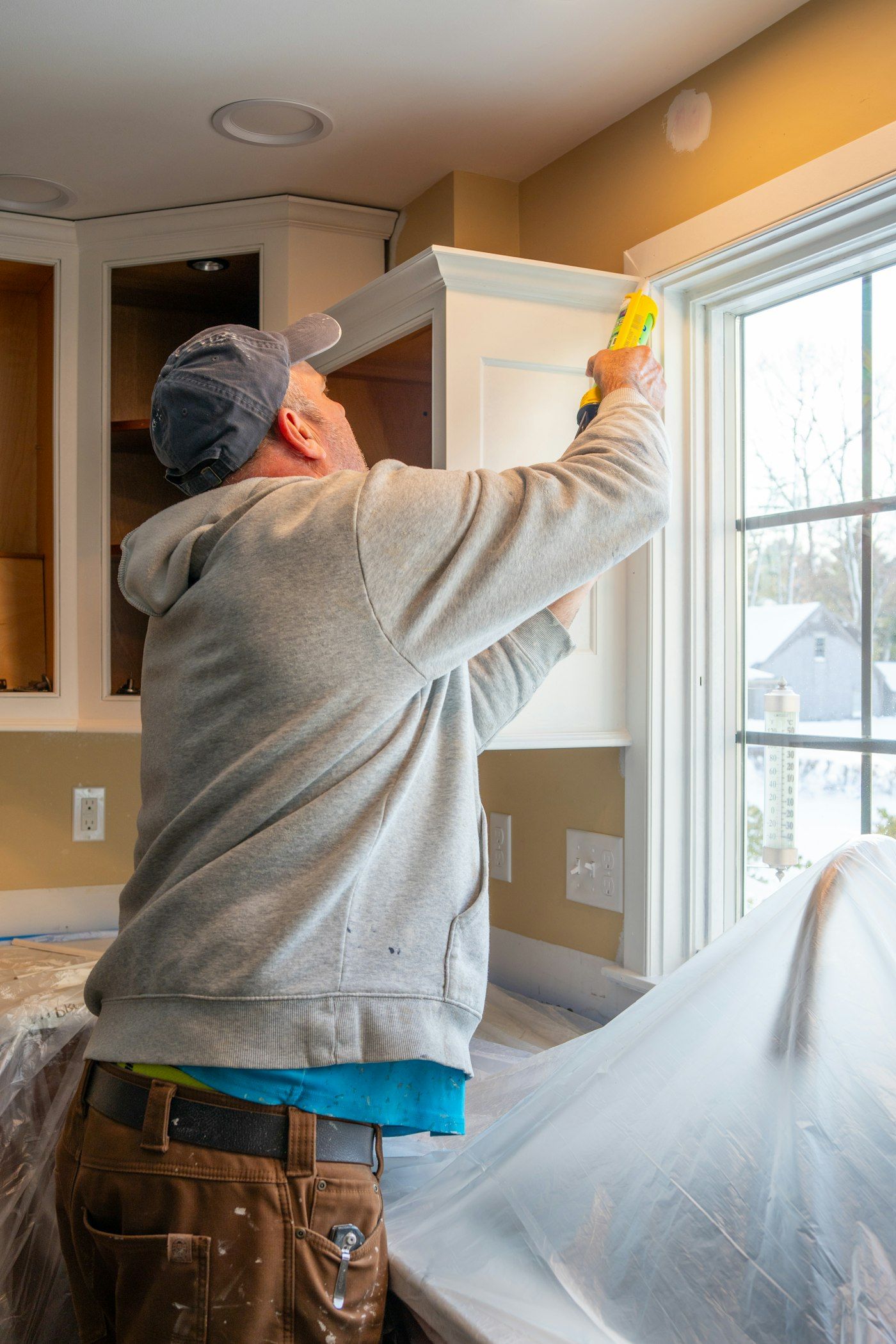 Jess caulking a window casing in a finished kitchen