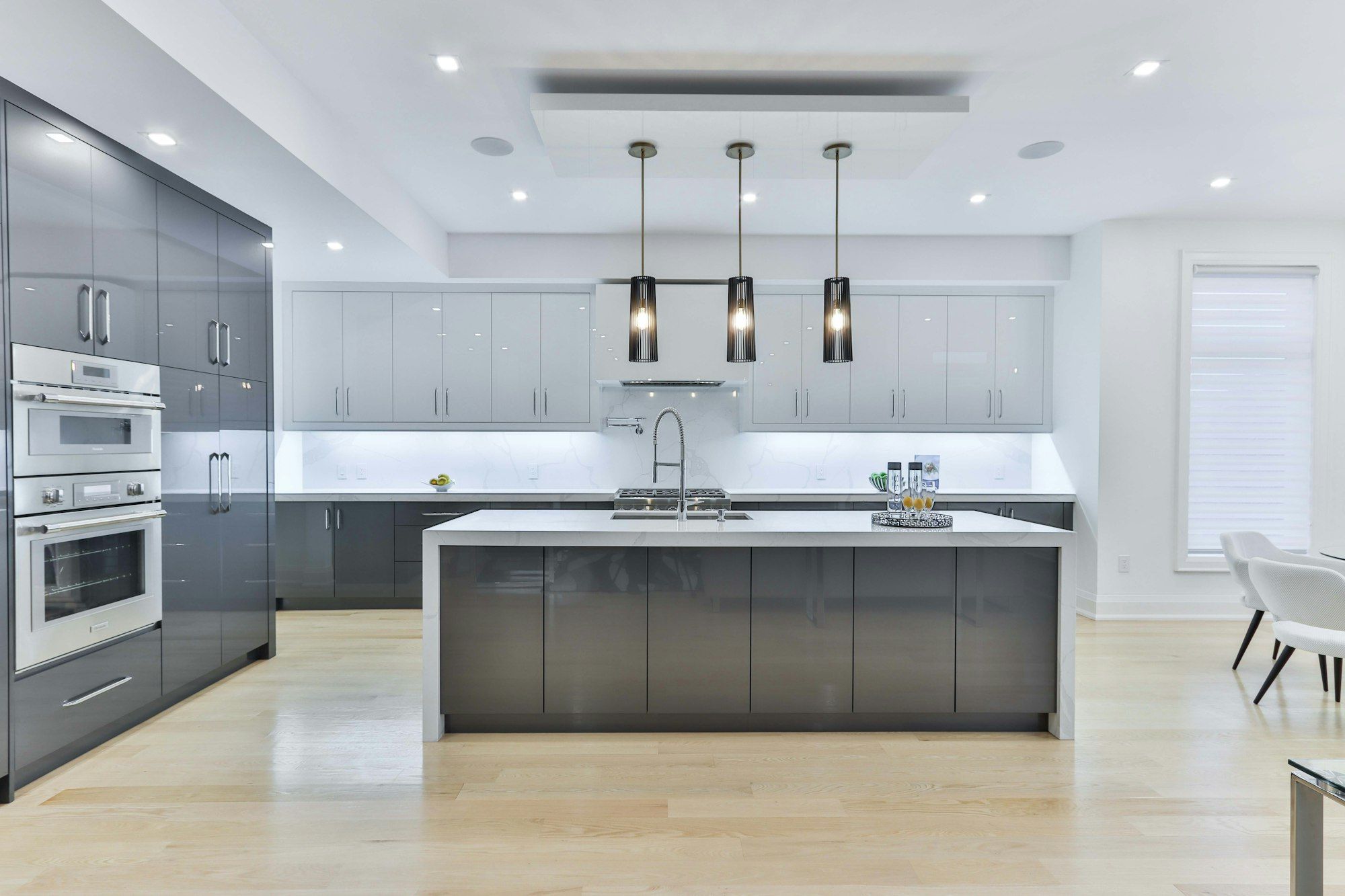 Open kitchen with a gray island and three pendants where a wall once stood