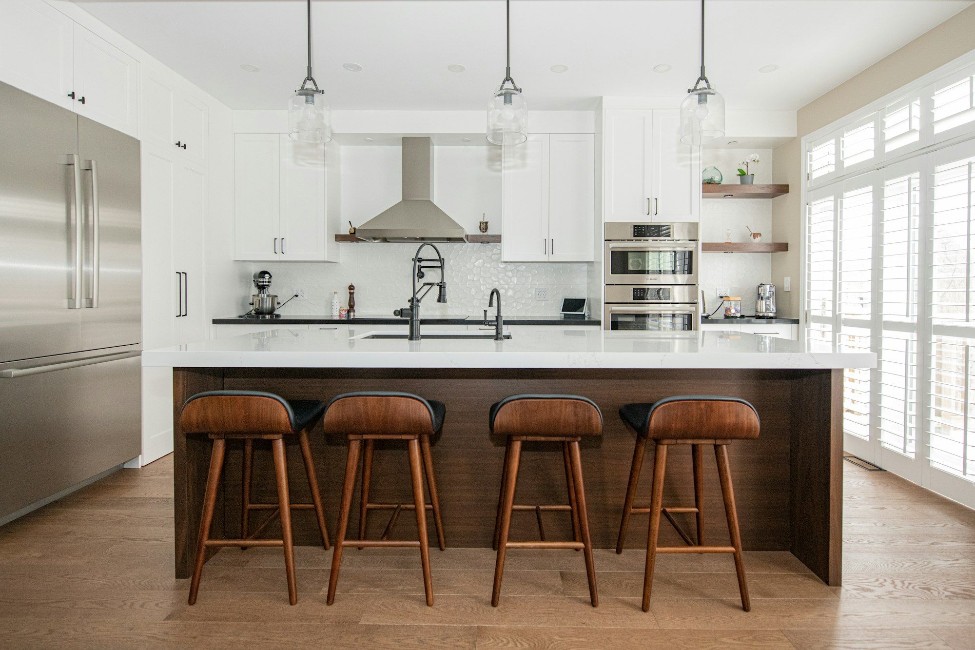 White kitchen with a walnut island and leather stools