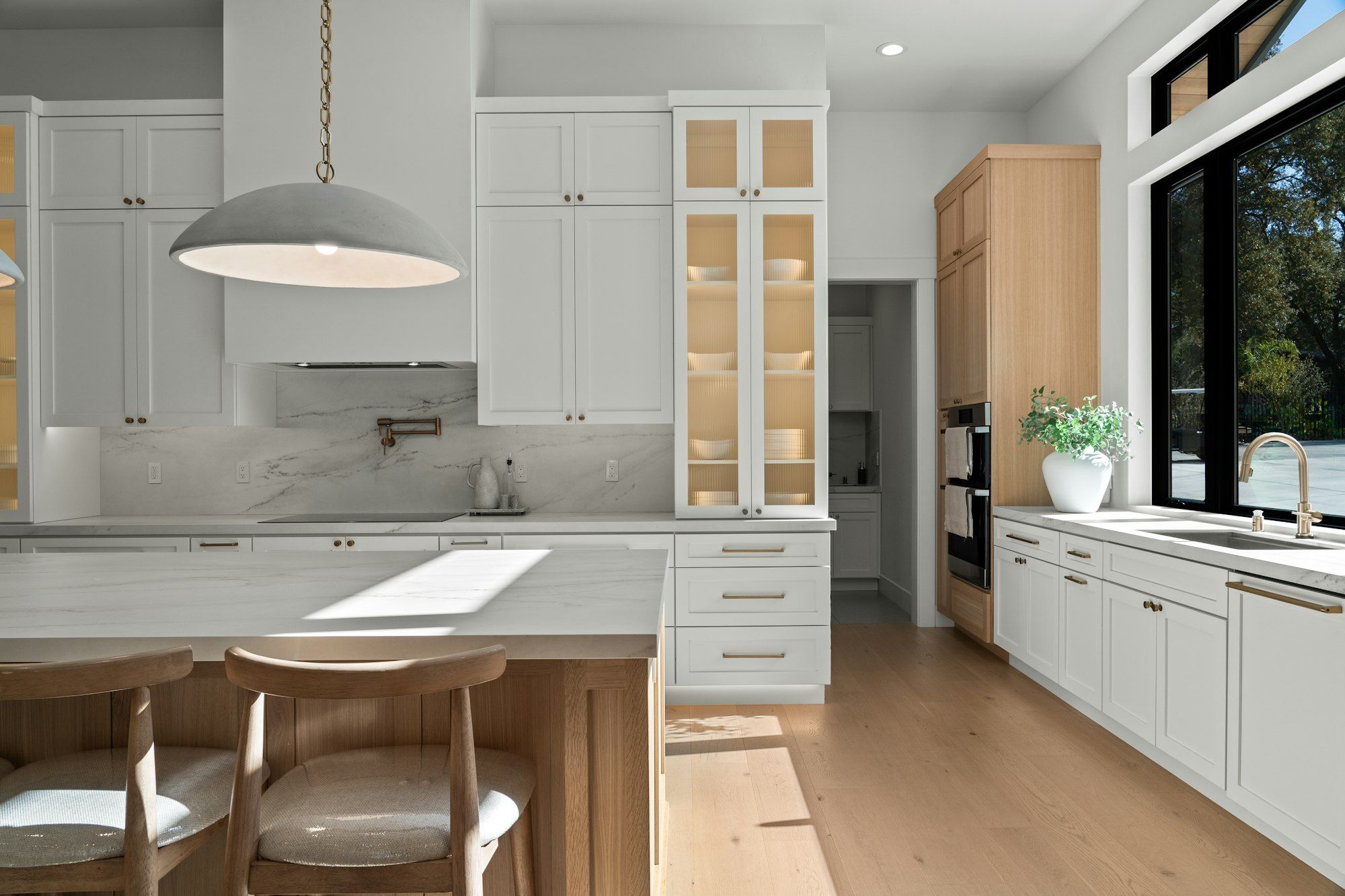 White kitchen with a long island, shaker cabinets and a large window