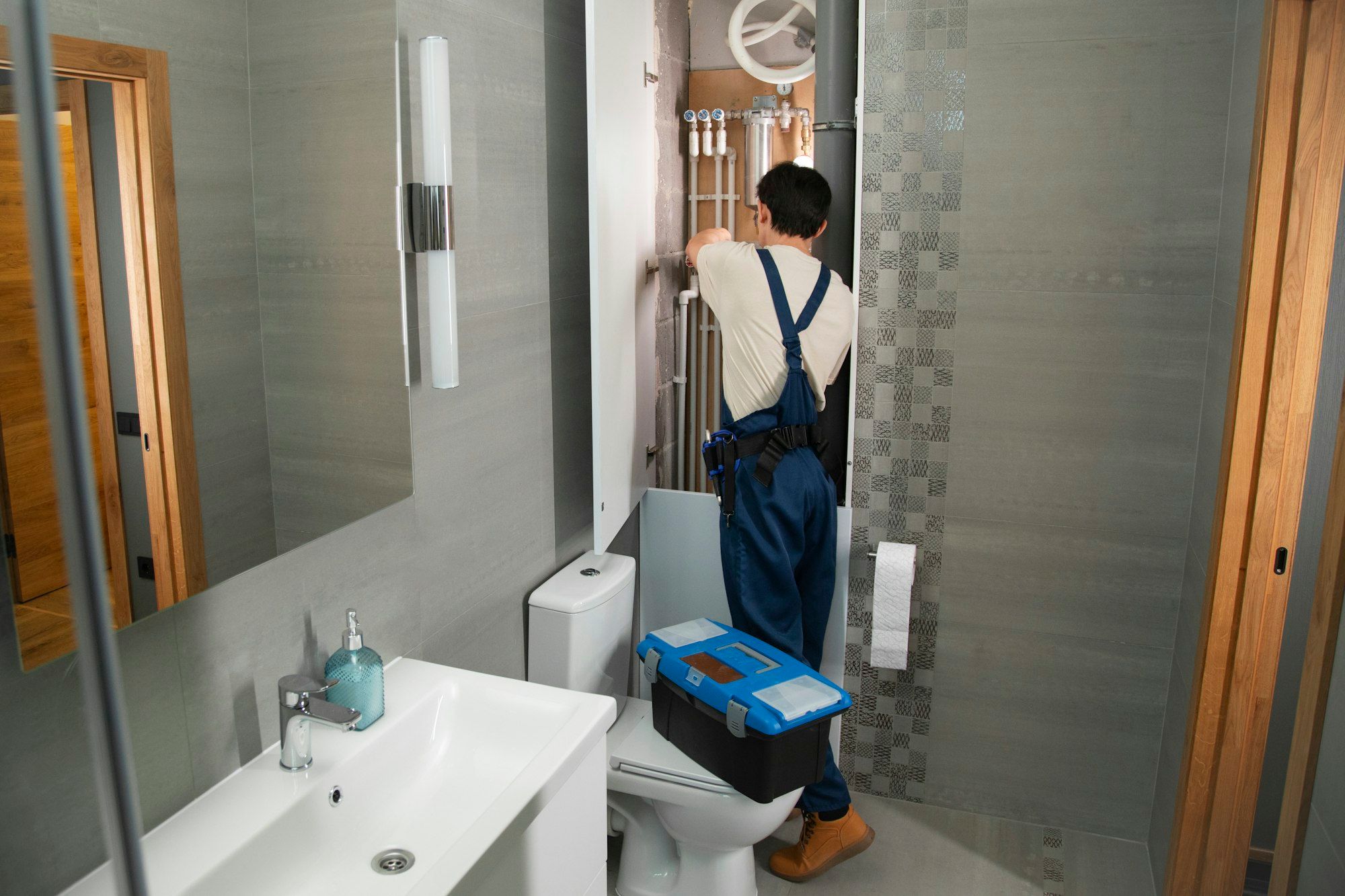 Summit plumber working on bathroom supply lines behind a toilet