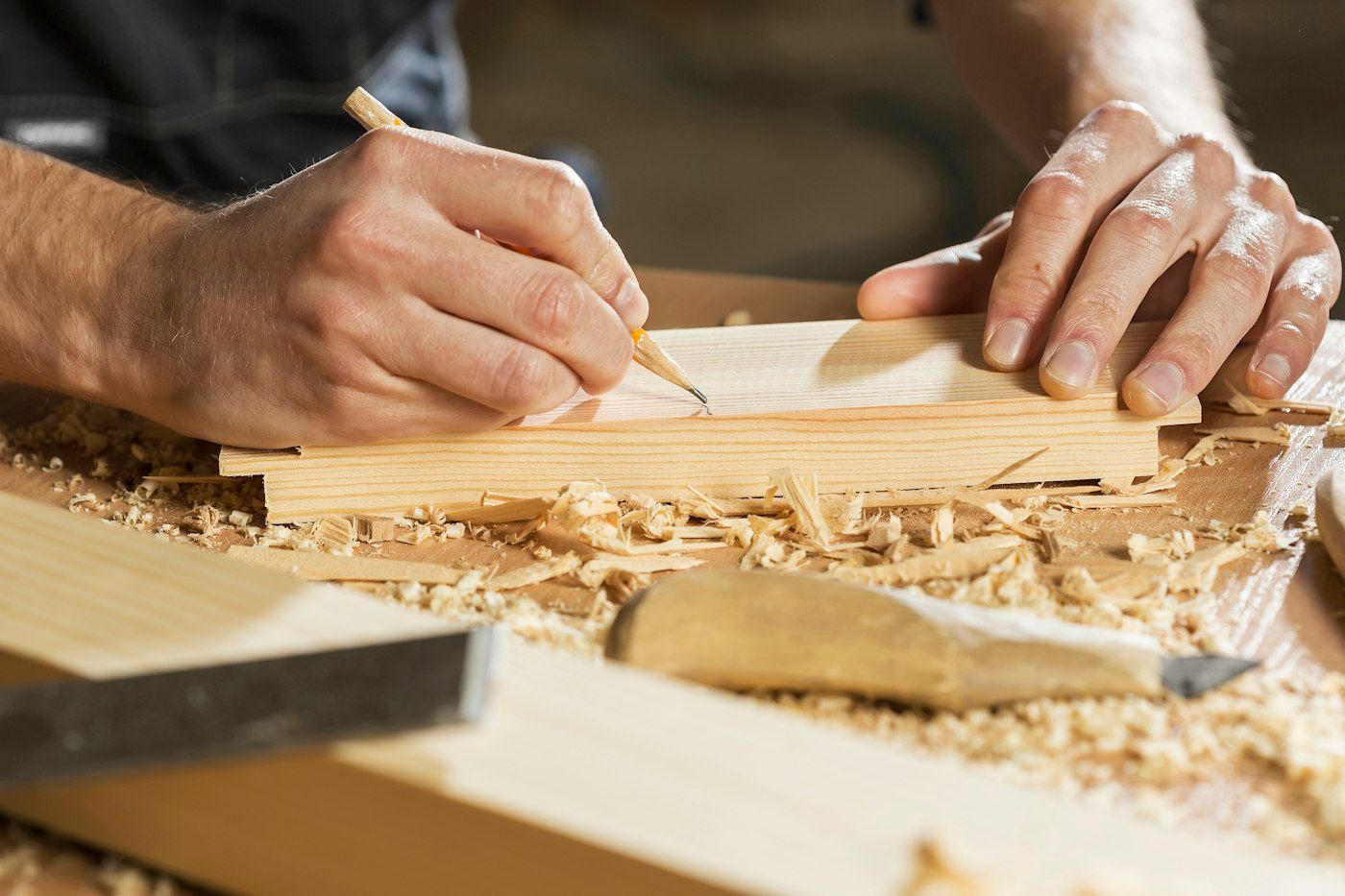 Hands marking a cut line on an oak board with a pencil