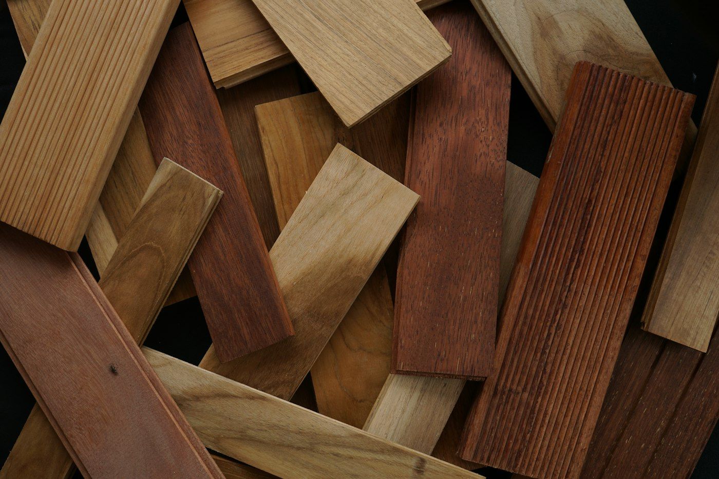 Pile of oak, teak and mahogany flooring sample boards in mixed tones