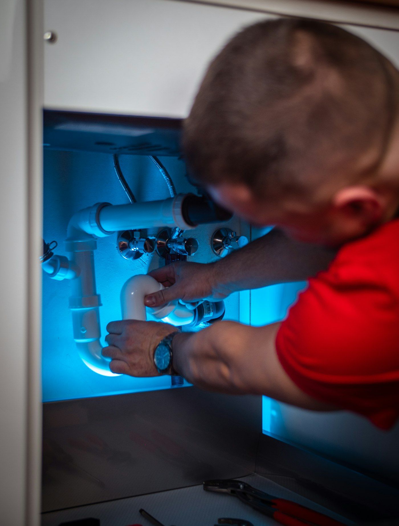 Plumber working on the drain line in a sink cabinet