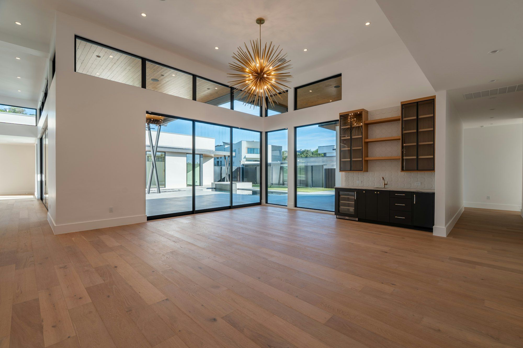 Great room with wide oak planks, a starburst light and glass doors