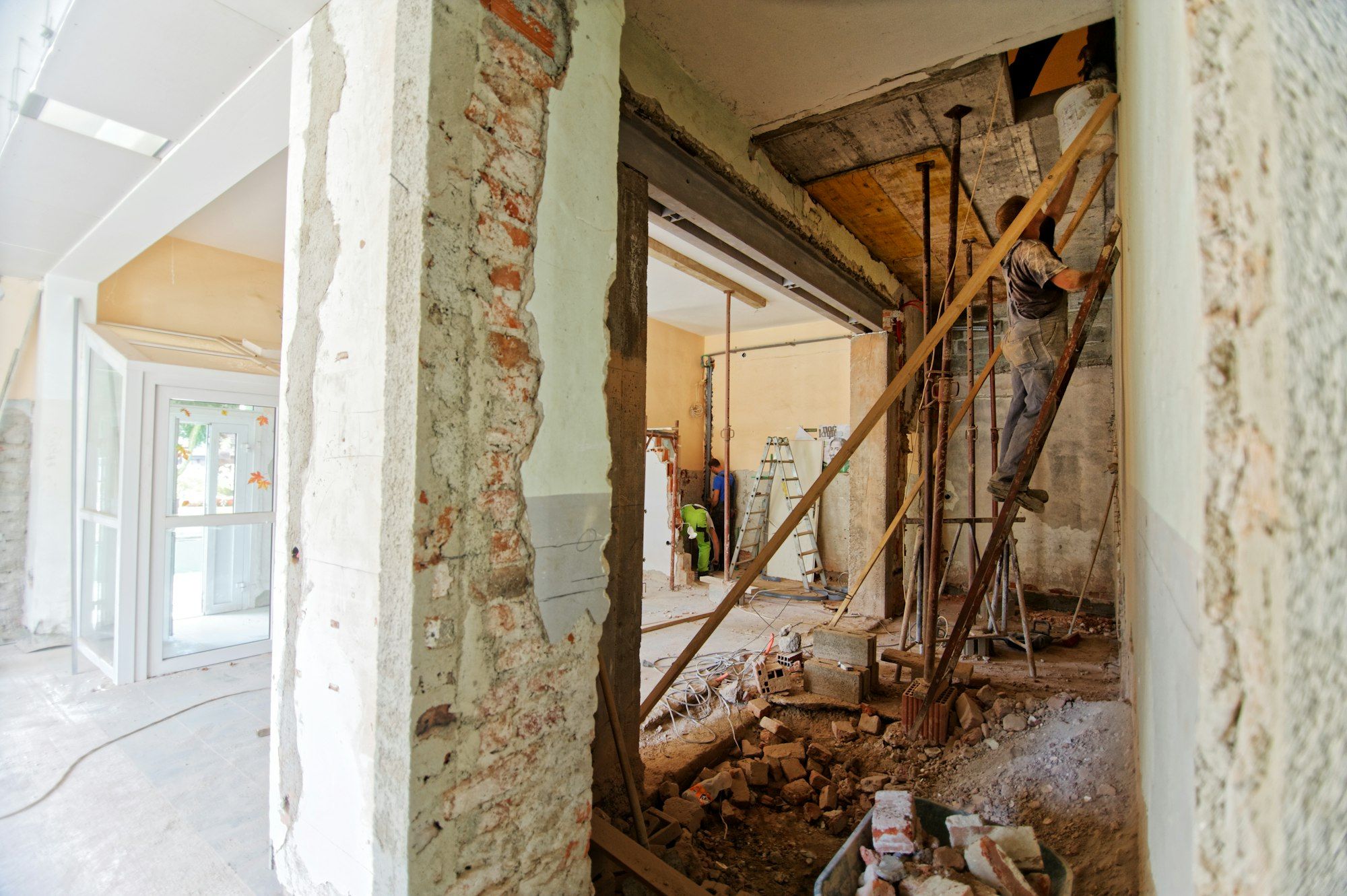 Wall opening with the new beam, shoring and a worker on a ladder