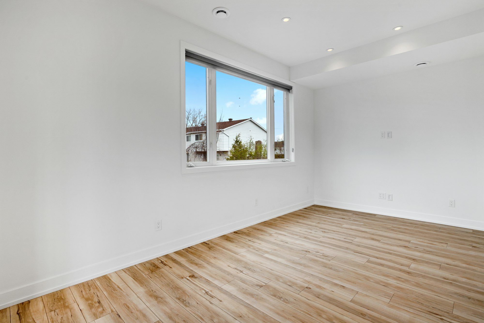Empty bedroom with varied light and amber hickory plank floor